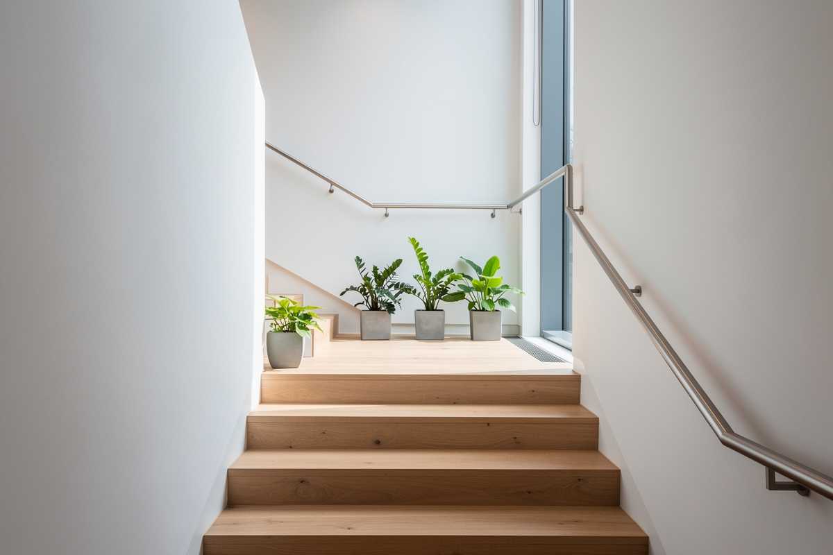 Eine Holztreppe mit hellen Stufen in einem lichtdurchfluteten Treppenhaus eines Bürogebäudes